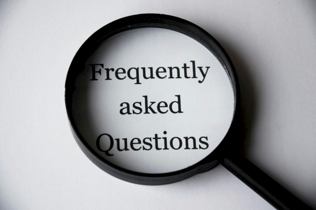 Faqs , Close-up of a magnifying glass focusing on the phrase 'Frequently Asked Questions'.