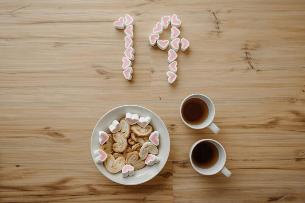 Heart-shaped marshmallows and cookies with two cups of tea, perfect for a romantic setting.